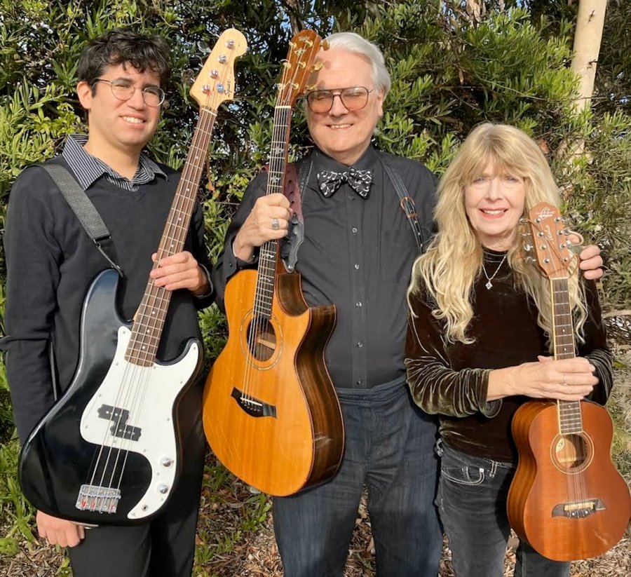 The Jeff Moyer Trio outdoors with their instruments: Luis Mireles with electric bass, Jeff Moyer with acoustic guitar, and Ellyn Quiggle with ukulele
